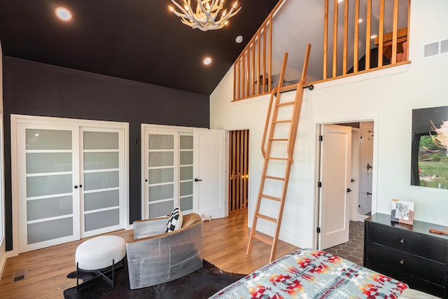 bedroom with wood-type flooring, high vaulted ceiling, and a chandelier