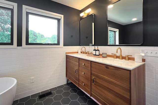 bathroom with tile patterned floors, vanity, a healthy amount of sunlight, and tile walls