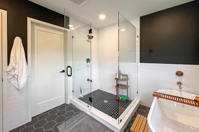 bathroom with tile patterned floors, separate shower and tub, and tile walls