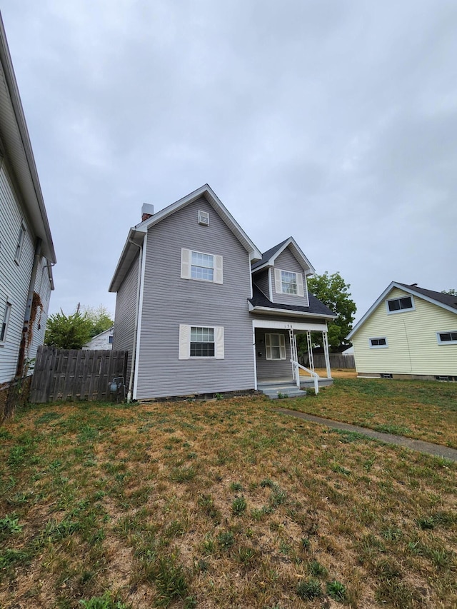 back of property featuring a yard and a porch