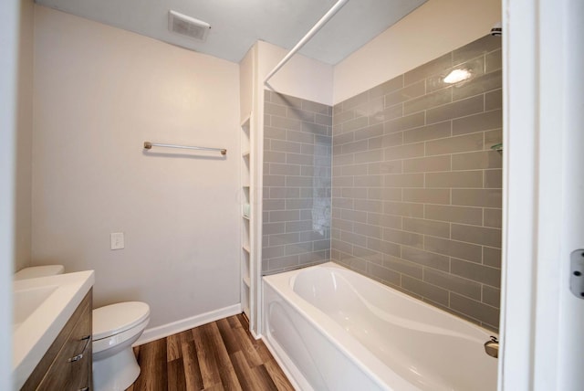 full bathroom with wood-type flooring, tiled shower / bath, vanity, and toilet