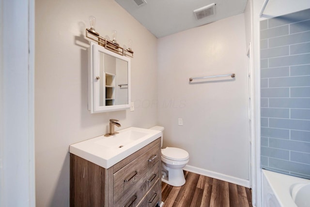 bathroom featuring vanity, a bathtub, wood-type flooring, and toilet