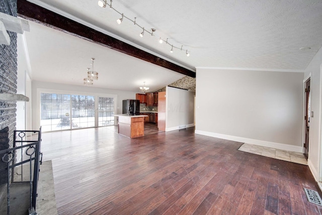 unfurnished living room featuring a fireplace, lofted ceiling with beams, dark hardwood / wood-style flooring, a notable chandelier, and a textured ceiling