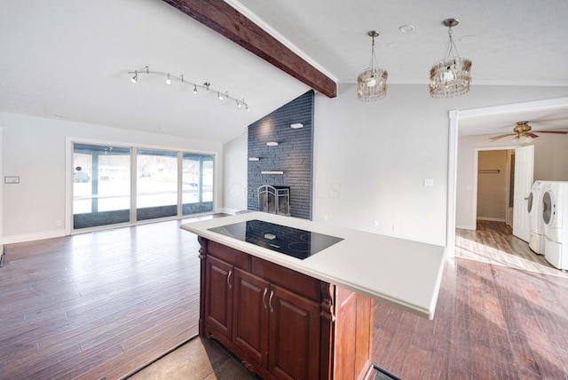 kitchen featuring a brick fireplace, washing machine and dryer, hanging light fixtures, and vaulted ceiling with beams