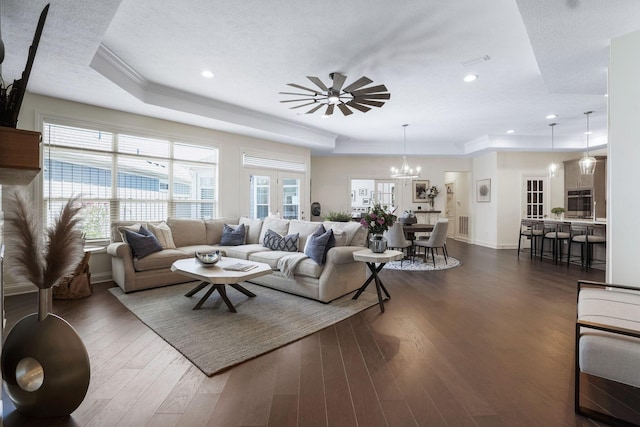 living room with a textured ceiling, dark hardwood / wood-style flooring, ceiling fan with notable chandelier, and ornamental molding