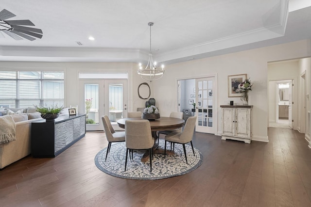 dining space with french doors, ornamental molding, ceiling fan with notable chandelier, a tray ceiling, and dark hardwood / wood-style floors