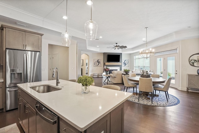 kitchen featuring ceiling fan with notable chandelier, sink, an island with sink, appliances with stainless steel finishes, and dark hardwood / wood-style flooring