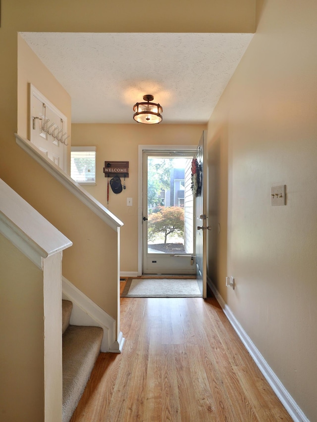 foyer entrance featuring light hardwood / wood-style flooring, a healthy amount of sunlight, and a textured ceiling