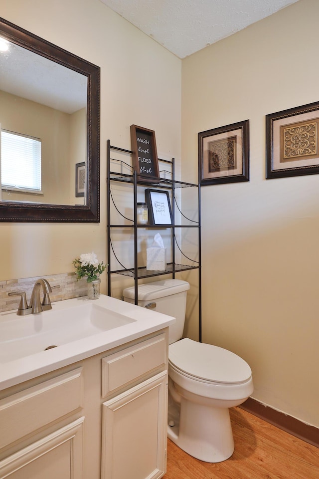 bathroom with hardwood / wood-style flooring, vanity, toilet, and a textured ceiling