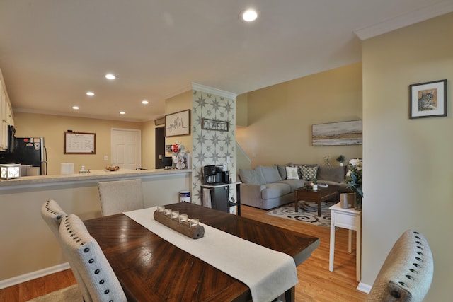 dining space with light hardwood / wood-style floors and ornamental molding