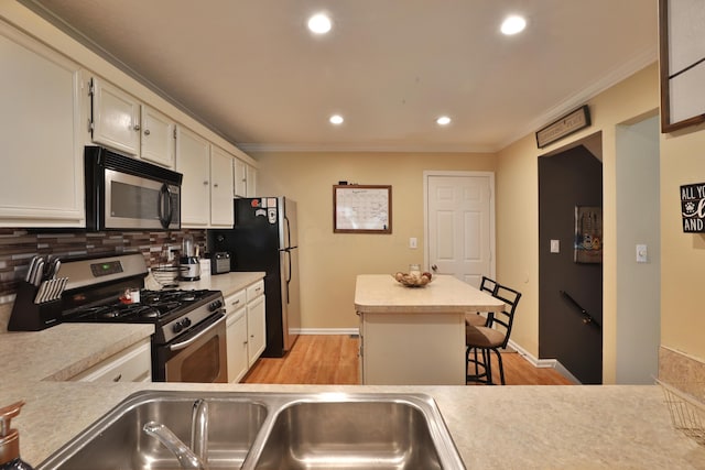 kitchen featuring a kitchen bar, decorative backsplash, crown molding, and appliances with stainless steel finishes