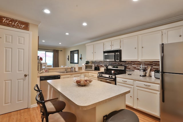 kitchen featuring light wood-type flooring, a breakfast bar, stainless steel appliances, sink, and a center island