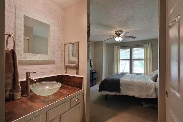 bedroom featuring ceiling fan, sink, carpet, and a textured ceiling