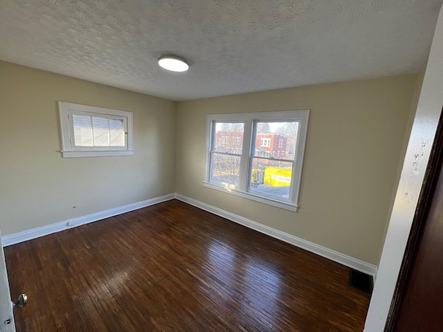 unfurnished room featuring dark hardwood / wood-style flooring and a textured ceiling