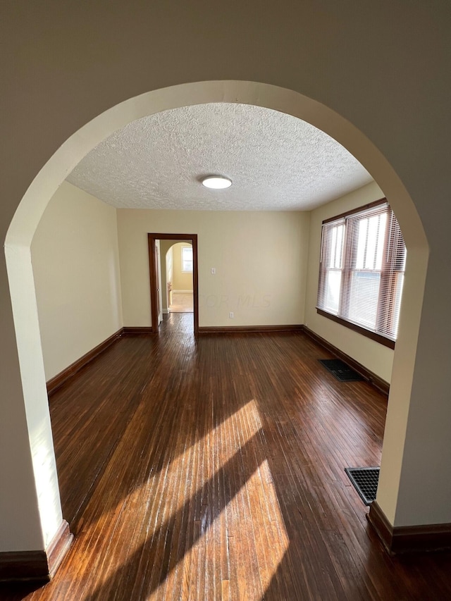 spare room with a textured ceiling and dark wood-type flooring