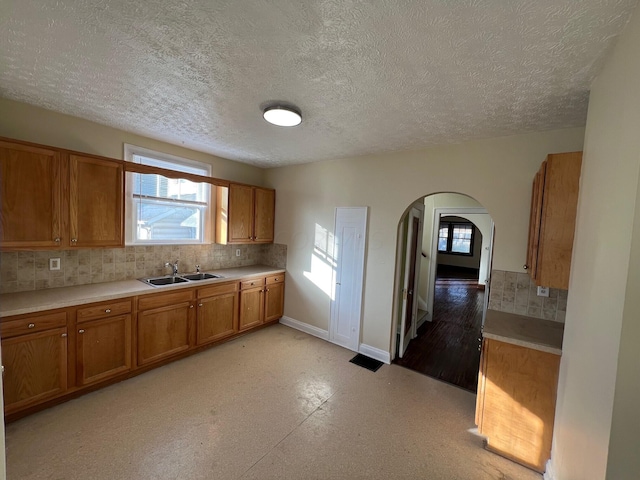 kitchen with a textured ceiling, plenty of natural light, sink, and tasteful backsplash