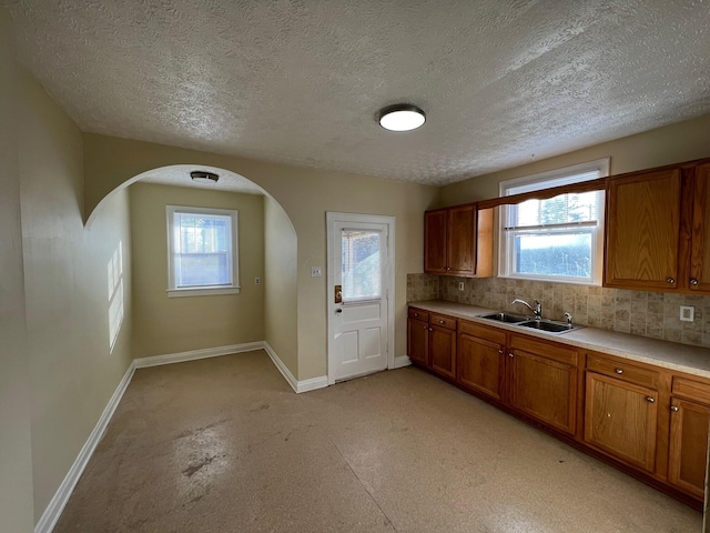 kitchen with a textured ceiling, tasteful backsplash, and sink