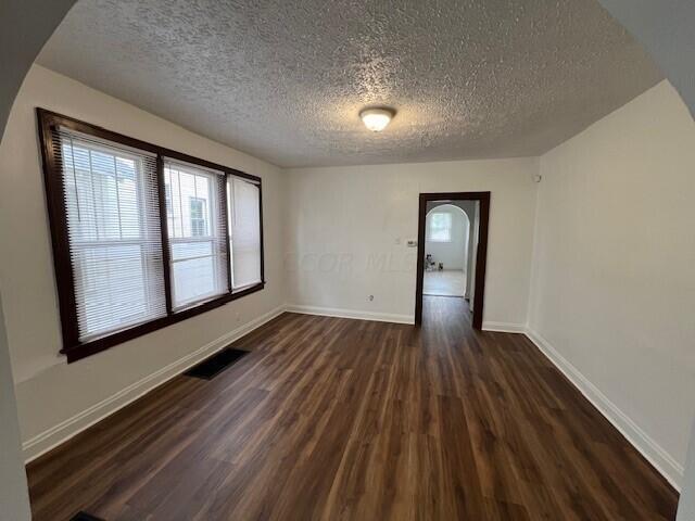 empty room with dark hardwood / wood-style floors and a textured ceiling