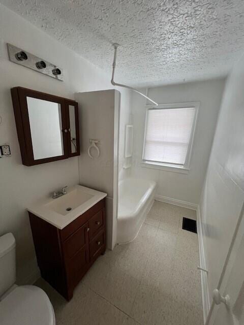 bathroom featuring vanity, a textured ceiling, and toilet