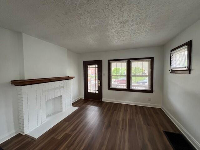 unfurnished living room featuring a textured ceiling, a wealth of natural light, and dark hardwood / wood-style floors