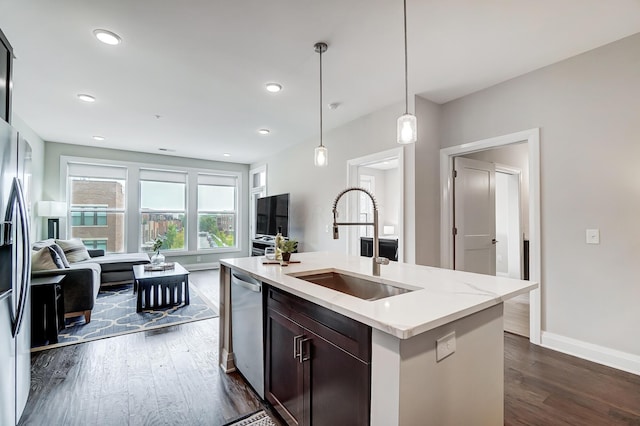 kitchen with sink, dark hardwood / wood-style flooring, stainless steel dishwasher, an island with sink, and pendant lighting