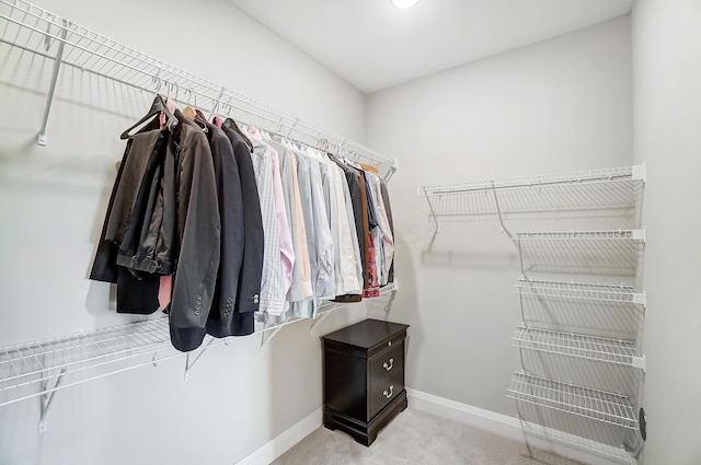 walk in closet featuring light colored carpet