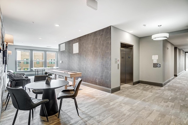 dining area with light wood-type flooring and elevator