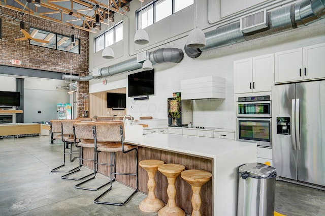 kitchen featuring white cabinets, stainless steel appliances, a high ceiling, and a breakfast bar area