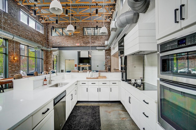 kitchen featuring a healthy amount of sunlight, sink, brick wall, and stainless steel appliances