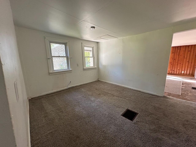 carpeted empty room with wooden walls