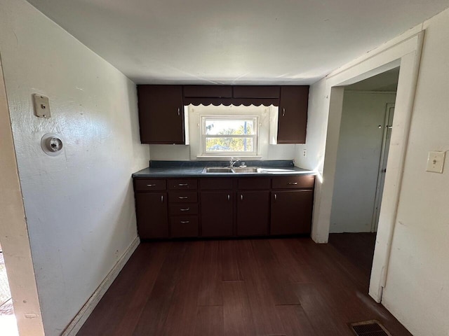 kitchen with dark brown cabinetry, sink, and dark wood-type flooring