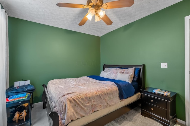 bedroom with ceiling fan, light colored carpet, and a textured ceiling