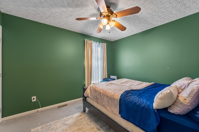 carpeted bedroom with ceiling fan and a textured ceiling