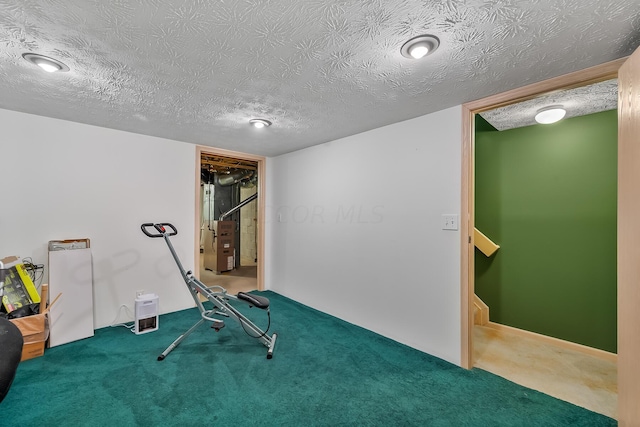 exercise area featuring carpet floors and a textured ceiling