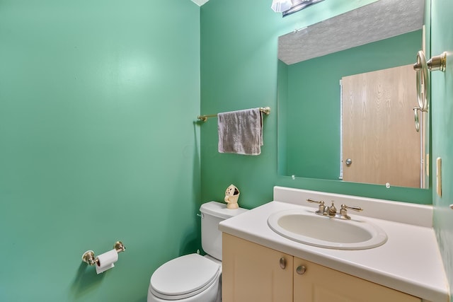 bathroom featuring a textured ceiling, vanity, and toilet