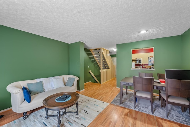 living room with sink, wood-type flooring, and a textured ceiling