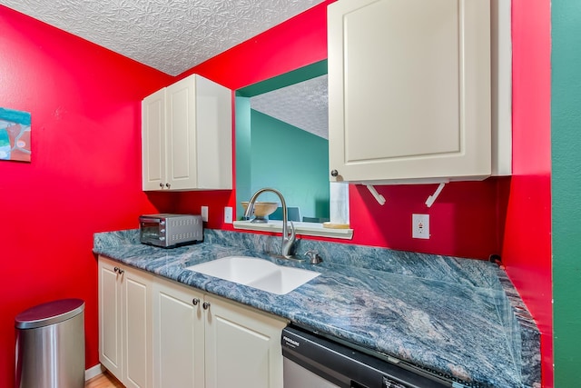 kitchen with a textured ceiling, sink, dishwasher, dark stone countertops, and white cabinets