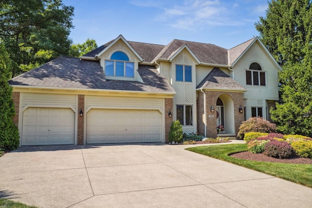 view of front of property featuring an attached garage, stucco siding, a shingled roof, concrete driveway, and brick siding