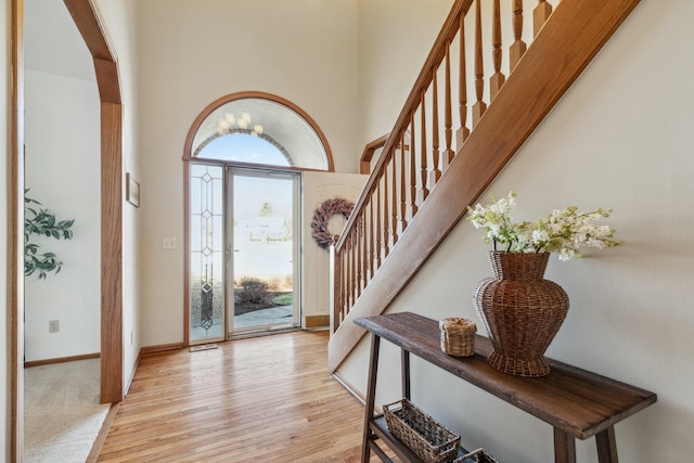 foyer with plenty of natural light, stairs, a towering ceiling, and wood finished floors