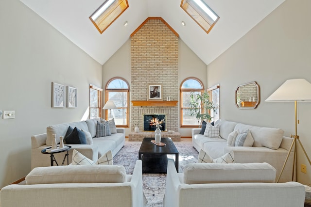 living room with a wealth of natural light, high vaulted ceiling, a brick fireplace, and a skylight