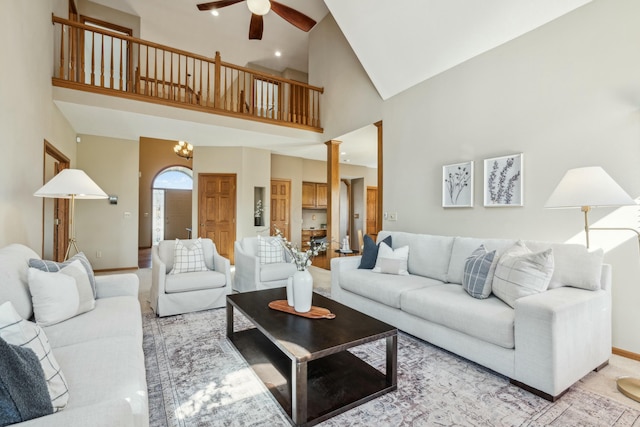 living area with baseboards, high vaulted ceiling, ceiling fan, and ornate columns