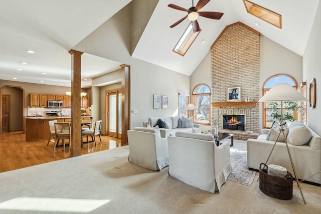 living room featuring a brick fireplace, a ceiling fan, recessed lighting, high vaulted ceiling, and ornate columns