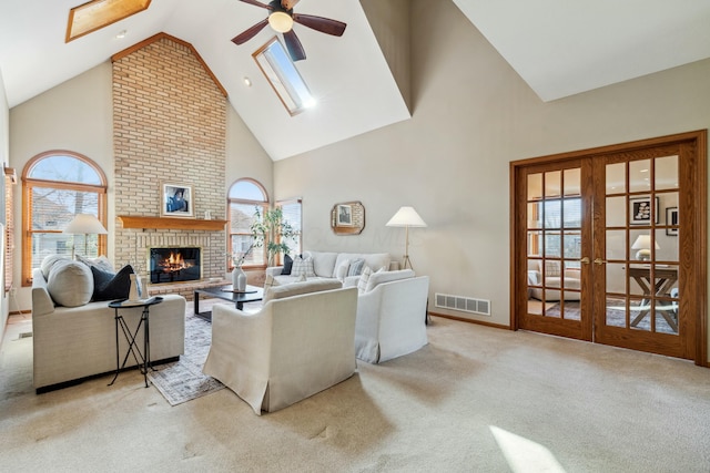 living area with visible vents, a skylight, french doors, a brick fireplace, and carpet flooring