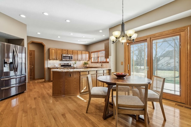 dining area featuring a notable chandelier, plenty of natural light, light wood-type flooring, and visible vents