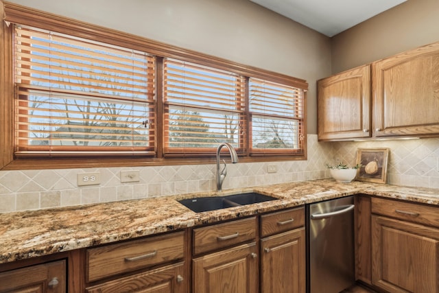 kitchen with tasteful backsplash, light stone countertops, and a sink