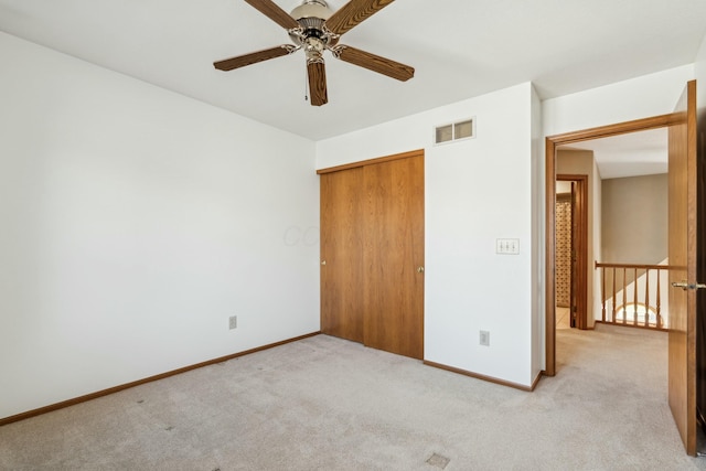 unfurnished bedroom featuring visible vents, baseboards, ceiling fan, a closet, and light colored carpet