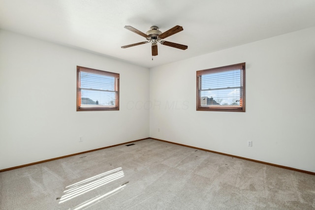 empty room featuring visible vents, light carpet, and baseboards