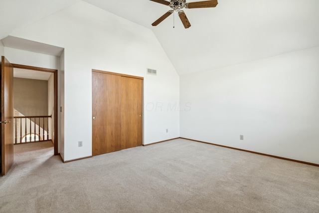 unfurnished bedroom featuring baseboards, visible vents, high vaulted ceiling, a closet, and carpet flooring