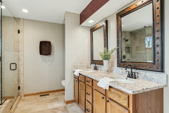 bathroom featuring a shower stall, baseboards, toilet, double vanity, and a sink