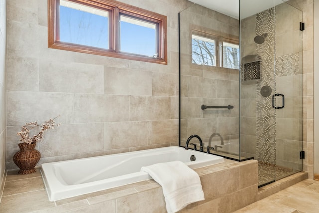 full bathroom with tile walls, a bath, and a stall shower